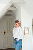 Blonde woman standing against white wall with mirror