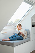 Blonde woman sits on bench in front of skylight