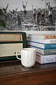 Coffee mug in front of a pile of books and a retro radio