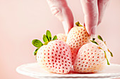 Frauenhand greift nach weißer Ananas-Erdbeere