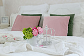 Tablett mit Blumen auf Doppelbett mit weißer Decke