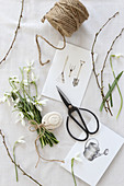 Snowdrops, scissors, drawings and string on a white surface