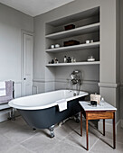 Freestanding bathtub under the shelf in the classic bathroom in grey