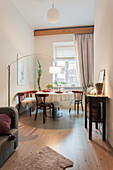 Arc lamp above round dining table next to window: seating area in the foreground