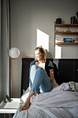 Blonde woman sitting with book on the bed