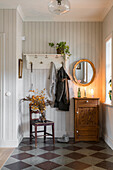 Wood paneled hallway with antique chest of drawers and tiled floor