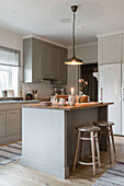 Kitchen island with counter height stools, pendant light above in farmhouse kitchen