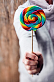 Hand holding colorful large swirl lollipop