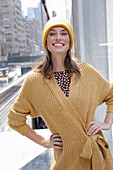 Joyful woman in yellow cardigan and hat