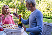 Älteres Paar beim Anstossen mit Rotwein am gedecktem Tisch