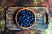 Bowl full of raw organic blueberry on wooden board