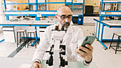 Scientist using a microscope and smart phone