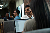 Happy businessman talking on smart phone in meeting