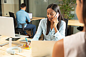 Businesswoman talking on cell phone at desk in office