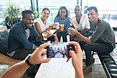 Man with smart phone photographing friends drinking beers