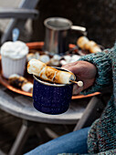 Enamel mug filled with hot chocolate and topped with a skewer of roasted marshmallows