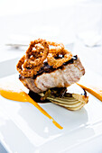 Grilled tuna with onion rings on plate
