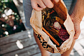 Person holding paper bag with food craps