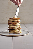 Spreading butter on a stack of pancakes