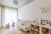 Bright nursery with cot and pink rocking animal