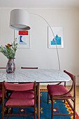 Arc lamp over dining table with marble top and upholstered chairs