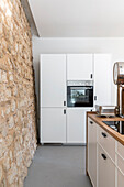 Kitchen with natural stone wall in an open room