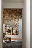 Rattan pouf and bookcase in front of natural stone wall in living room