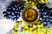 Georgischer trockener Weißwein im Glas daneben frische Trauben