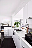 Modern, white fitted kitchen cabinets in open-plan living room