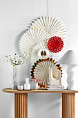 DIY paper rosettes on the wall above a console table with decorative objects