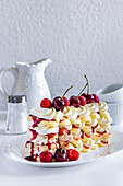 Raspberry tiramisu, layers of sponge, cream and fruit sauce, decorated with fresh raspberries and cherries