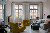 Sofa and designer armchair in the living room of an old building with stucco moulding