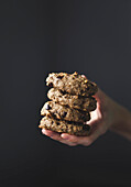 a hand holding a stack of chocolate chip cookies