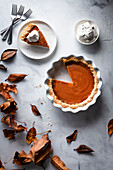 Pumpkin pie on a marble surface with whipped cream