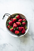Schüssel mit frischen Erdbeeren auf Marmoruntergrund