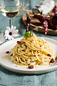 Spaghetti with salted codfish and chilli pepper, on a white ceramic plate