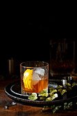 An Old Fashioned cocktail served over ice with a trist of lemon