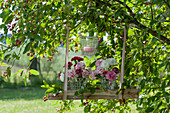 Small bouquet of carnations on wooden coaster and lantern hung on a rock pear tree