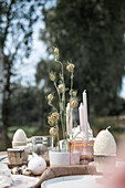 Ostertisch mit Kerzen und Blüten im Garten