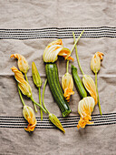 Fresh raw zucchini flowers on dark blue linen tablecloth