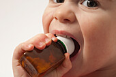 Young child putting a medicine bottle in his mouth