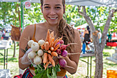 Woman holding vegetables on sale at a farmers market