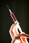 Hand gently squeezing a hypodermic syringe