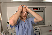 Stressed surgeon holds his head in his hands
