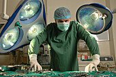 Surgeon standing over a tool laden operating table