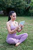 Young sportswoman using tablet outdoors