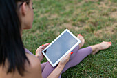 Young woman using digital tablet sitting on grass