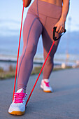 Woman in sportswear doing stretching exercise by expander
