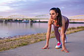 Young sprinter woman practicing start at riverbank