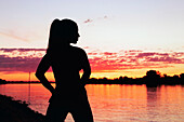 Silhouette of a woman at a riverbank at sunrise